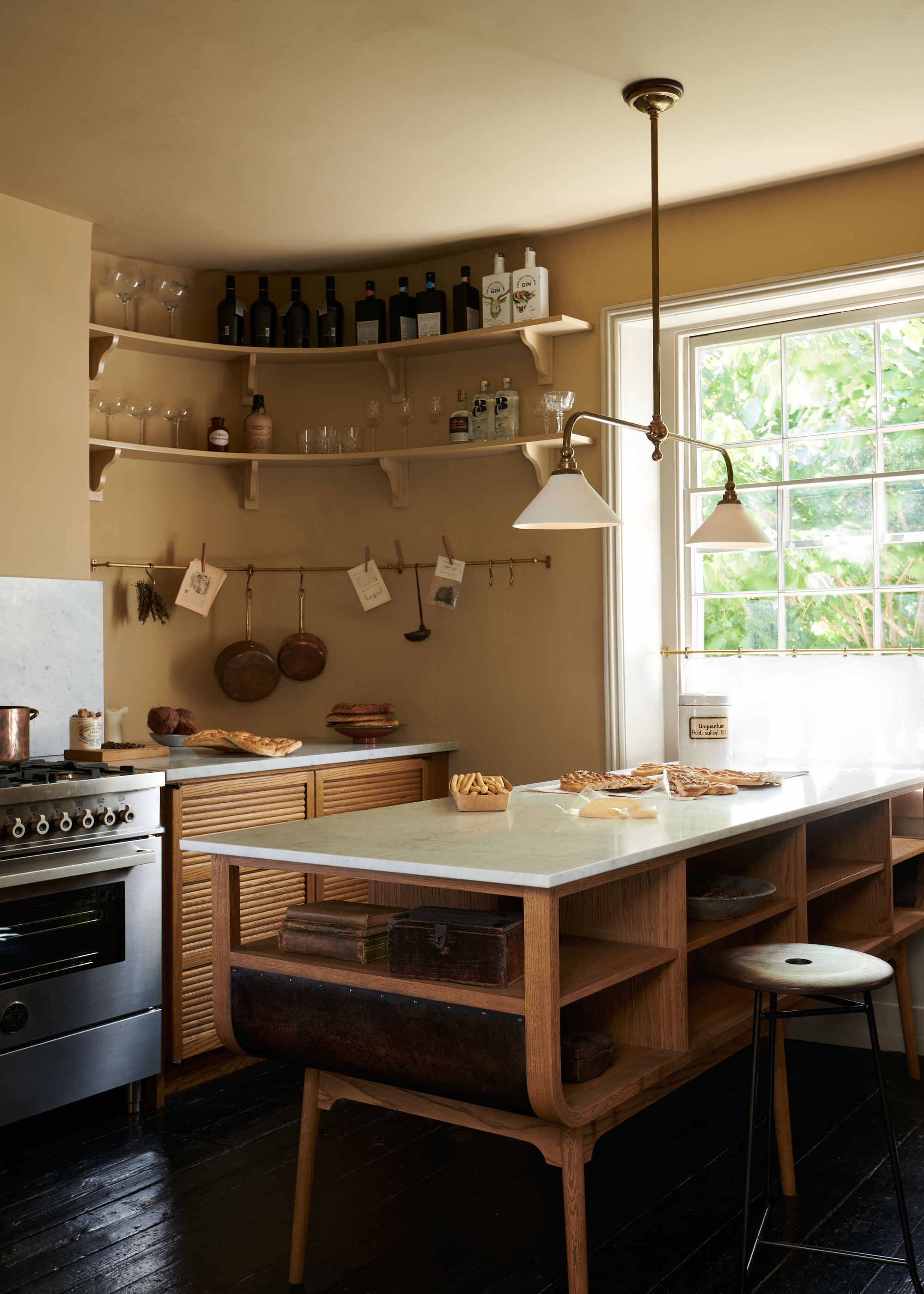 A kitchen with yellow-beige walls, a wooden island with cubby holes, and corner shelving on the walls