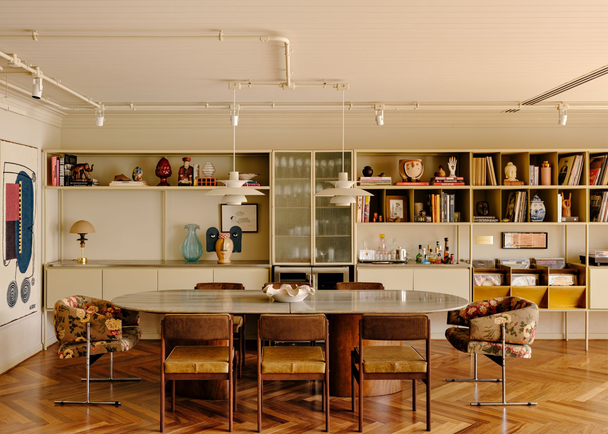A dining room with a patterned floor in wood, an oval dining table and chairs