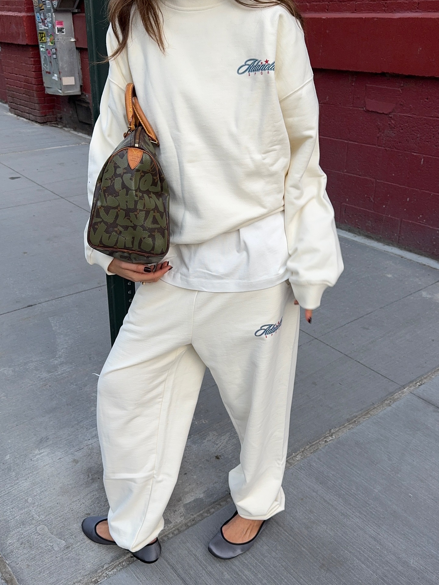 Influencer @rubylyn_ poses outside holding a Louis Vuitton Speedy bag.