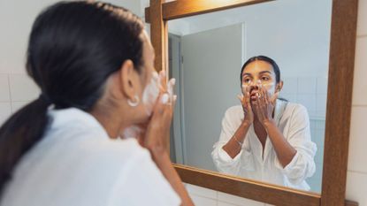 best Cleanser for dry skin - woman washing her face in the mirror