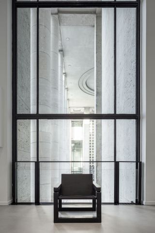 Black wooden chair in front of large glass window with black frame
