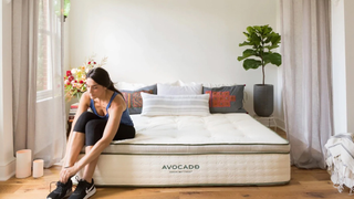 Lady putting her shoes on sitting on an Avocado Mattress