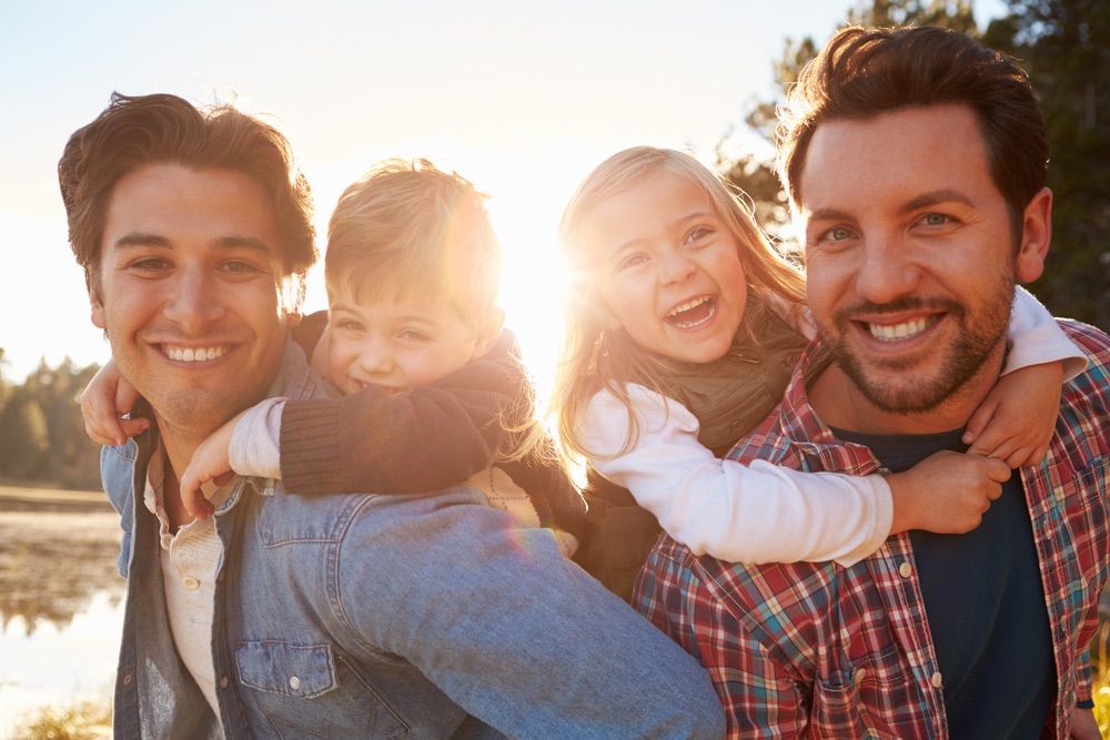 Gay dads with two kids at a park.