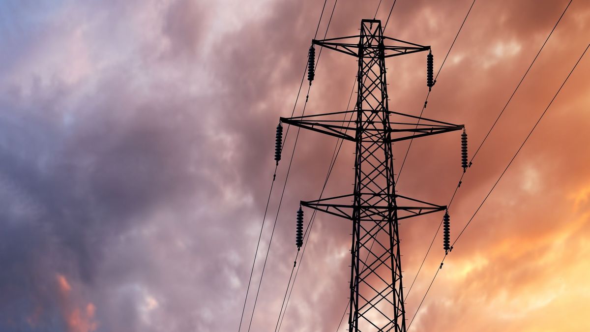 A British Style Electricity Pylon and suspended electric cables against a Blue Cloudy Sky