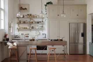 Bright and minimal white kitchen with long stainless steel counters and industrial metal open storage
