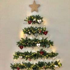 Wall mounted Christmas tree with fairy lights and red and white decorations
