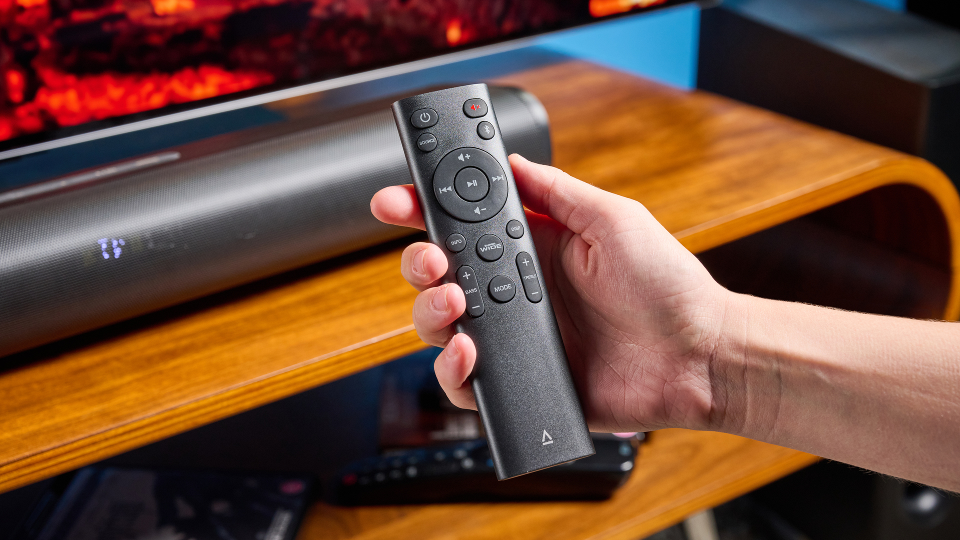 the creative stage pro soundbar and subwoofer, a super-budget home cinema system with 2.1 channels and a remote control photographed on a wooden tv stand with a TV behind
