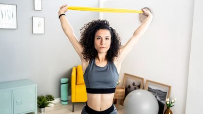 Woman doing an overhead press with a resistance band.