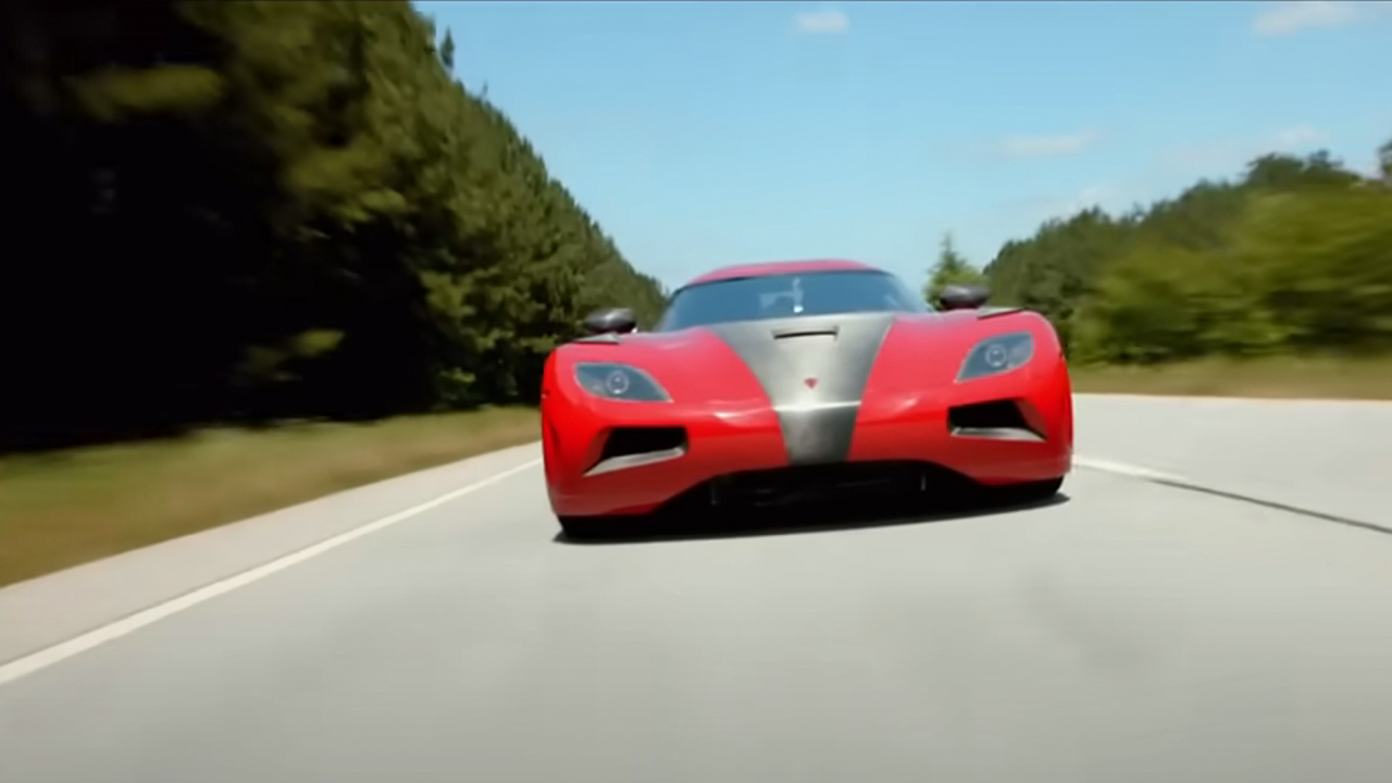 A red and grey car speeding down a road in Need for Speed