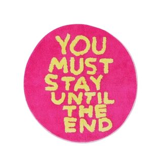 A pink circle rug that says 'you must stay until the end'