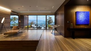 Sequoia penthouse by Gantous Arquitectos features wood floors and floor to ceilings patio windows leading to outside patio seating and a view of the hills.