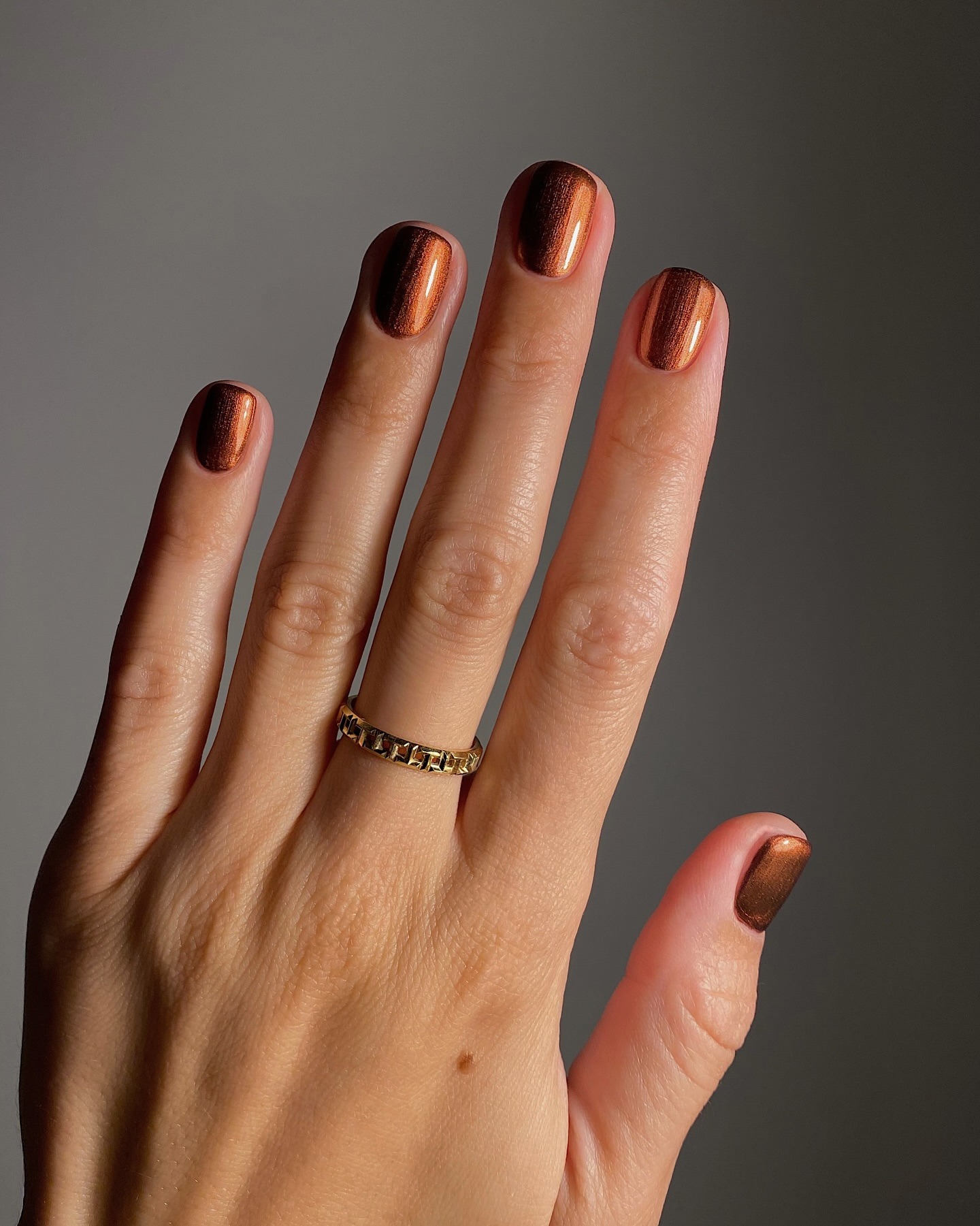 A short, shimmery, cinnamon-coloured manicure