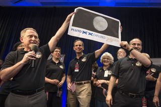 New Horizons principal investigator Alan Stern (left) with a print of a U.S. stamp with a suggested update after the New Horizons spacecraft explored Pluto in July 2015.