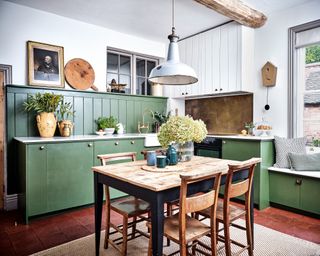 kitchen diner with green cabinets and tongue and groove, terracotta floor tiles and wooden table and chairs