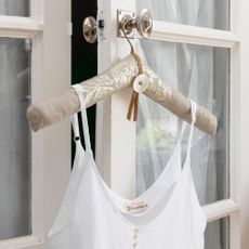  padded coat hanger with white silk dress hung on door