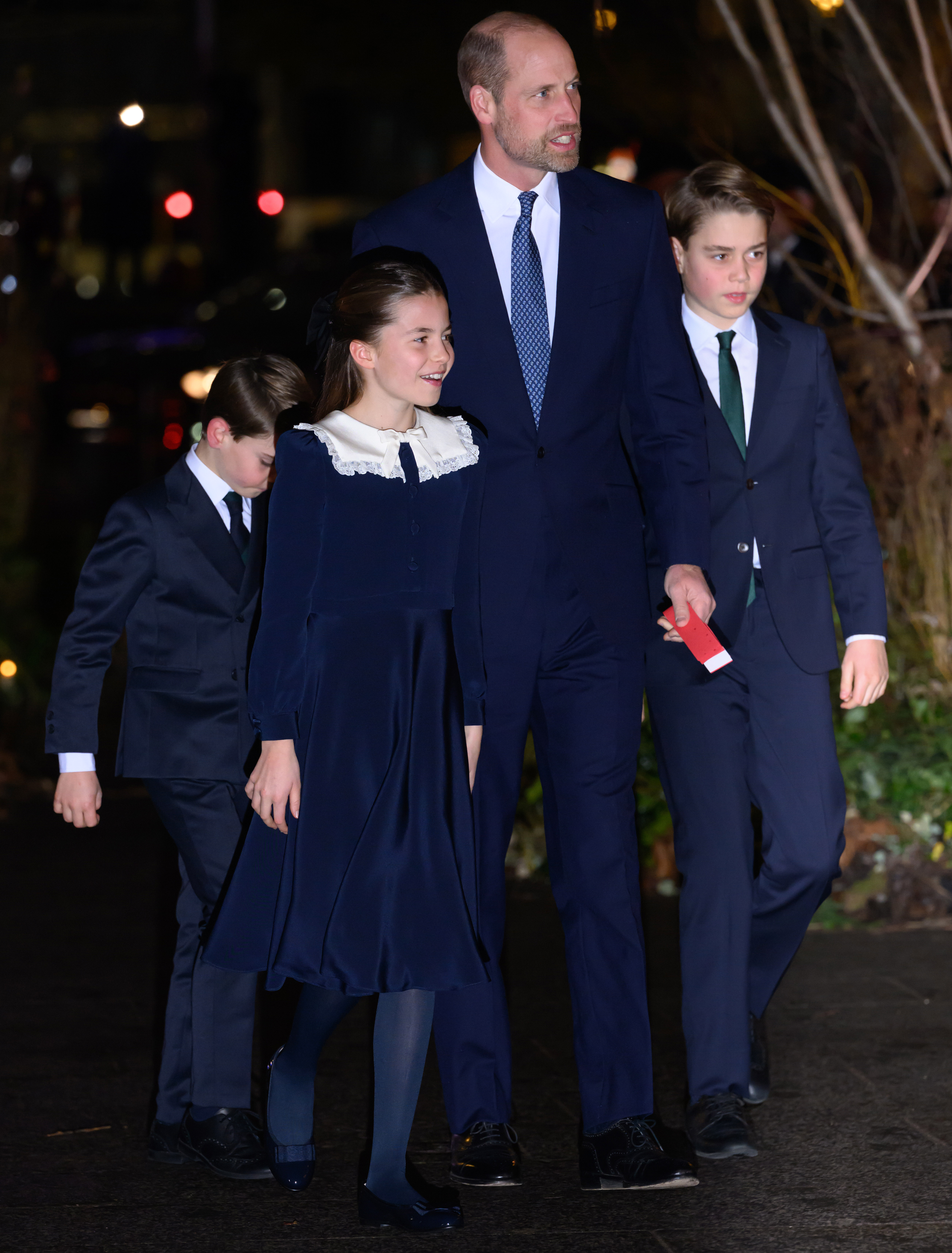 Prince William in a blue suit walking with Prince George, Princess Charlotte and Prince Louis