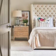 beige bedroom with beige carpet, walls, and furniture with a large bed in the forefront