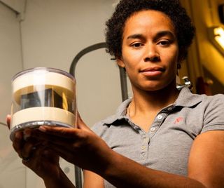 Brittany Robertson holding the Pacific Northwest National Laboratory's cube, which is enclosed in a protective case.