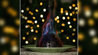 Flaming Christmas pudding with bokeh fairy lights in background