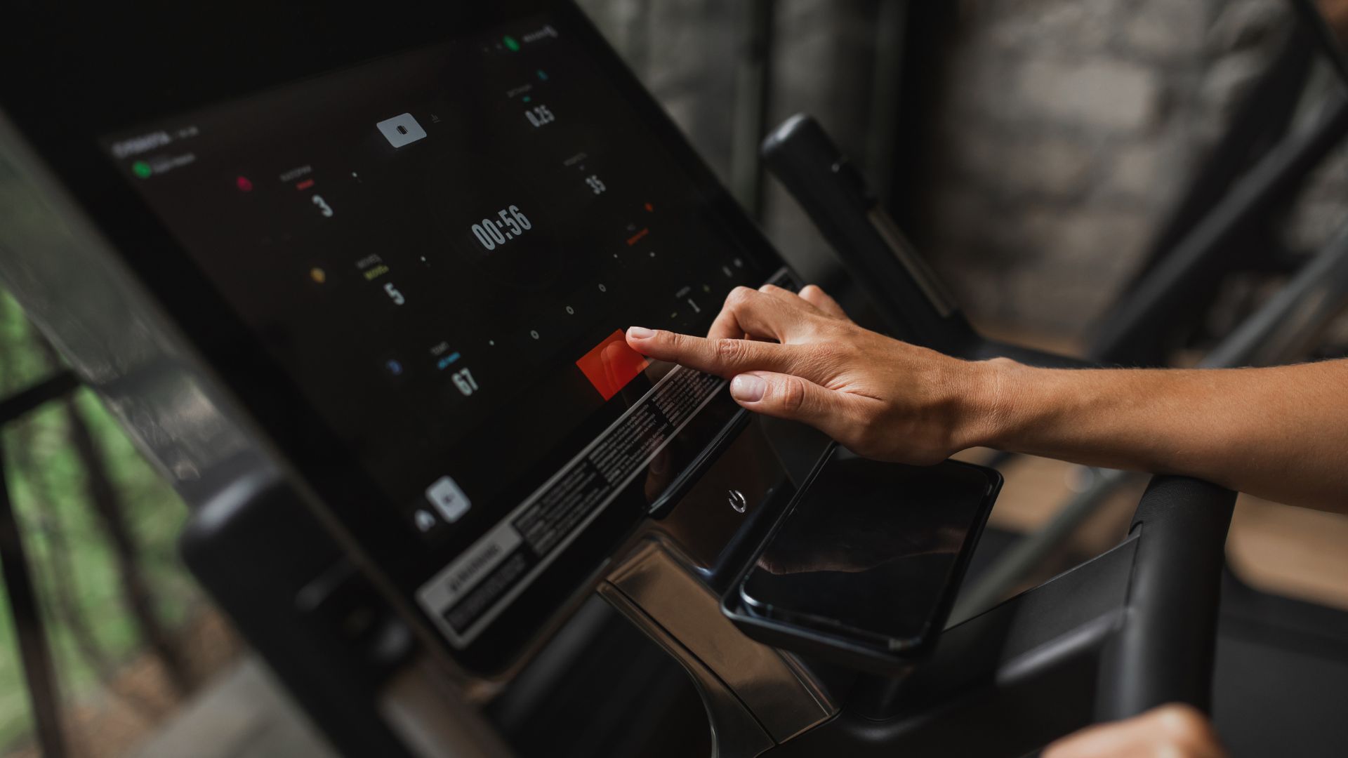 Woman pressing button on a screen during a treadmill workout