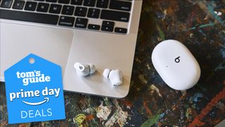 beats studio buds in white on top of a macbook keyboard with a prime day deal tag