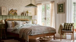 A shot of a bedroom with floral wallpaper and natural fabrics with a large patio door on the right-hand side