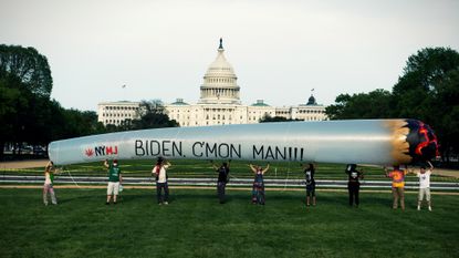 Pro-marijuana protesters hold a giant inflatable joint in front of Congress