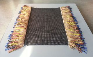 A black rug with colorful tassels on both sides.