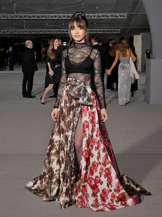 Lily Collins attends the 2nd Annual Academy Museum Gala at Academy Museum of Motion Pictures on October 15, 2022 in Los Angeles wearing a sheer black turtleneck top and floral-print skirt from Dior along with Cartier jewelry and Christian Louboutin Movida Sabina platform heeled sandals