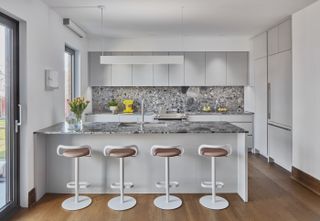 A kitchen with four white counter stools with adjustable heights