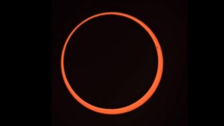 a ring of orange light that is the sun, it is against a black background.