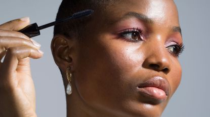 Best lengthening mascara - picture of a black woman with hot pink eyeshadow applying mascara