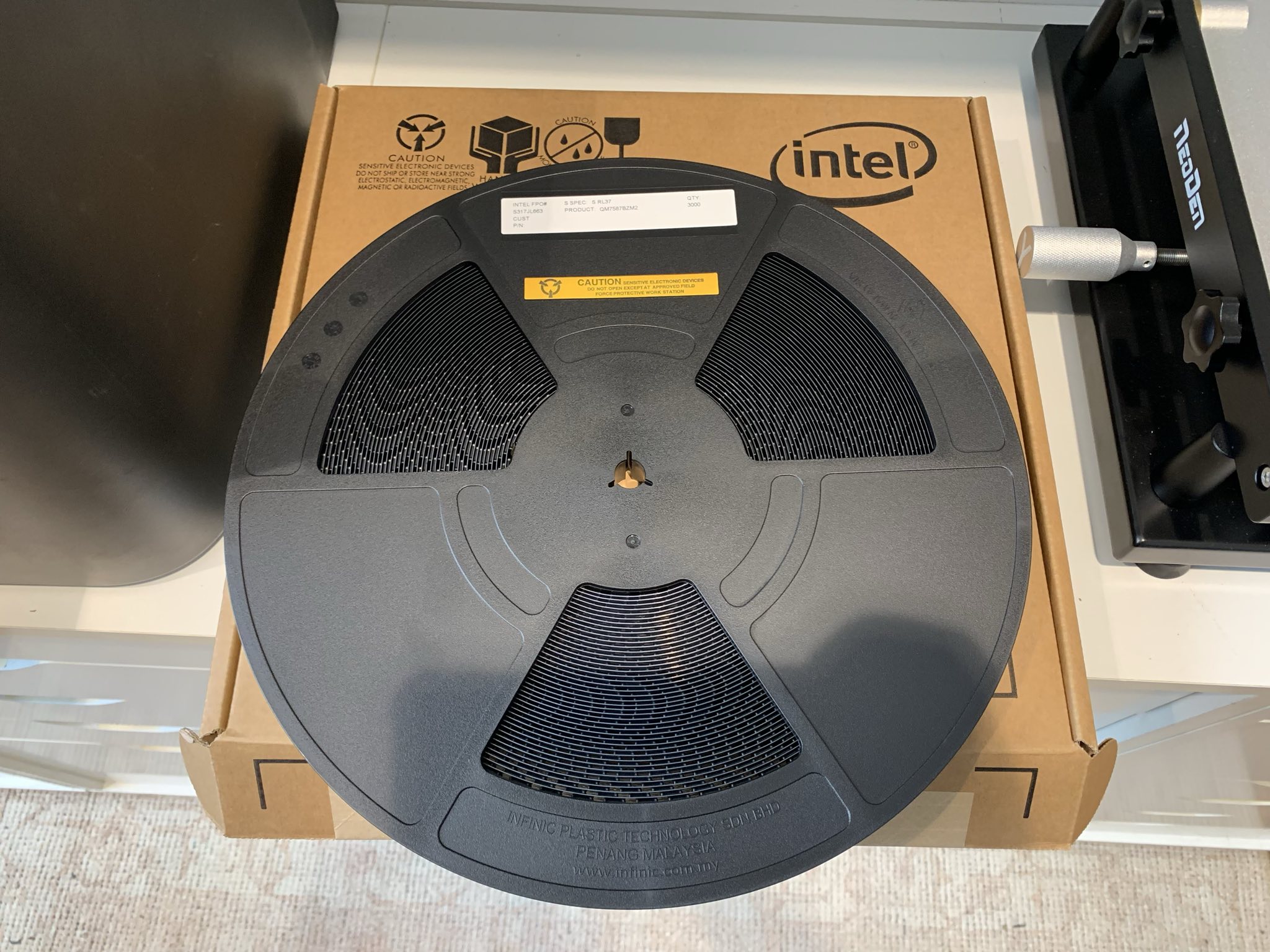 A reel of BZM2 ASICs placed on top of a box marked 'Intel'