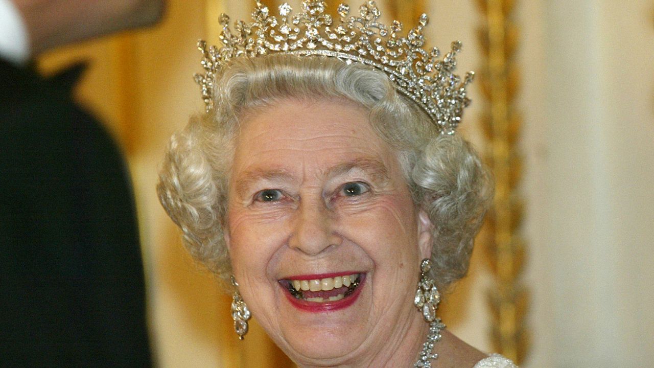 Queen Elizabeth smiling and wearing a diamond tiara and earrings