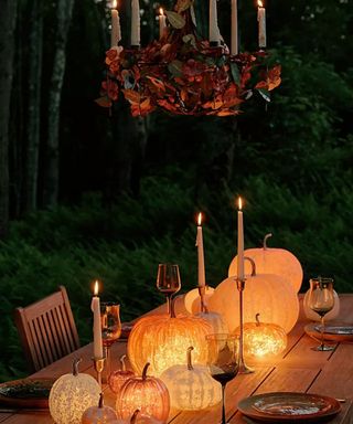 outdoor tablescape with lit pumpkin lights and a spooky candle chandelier