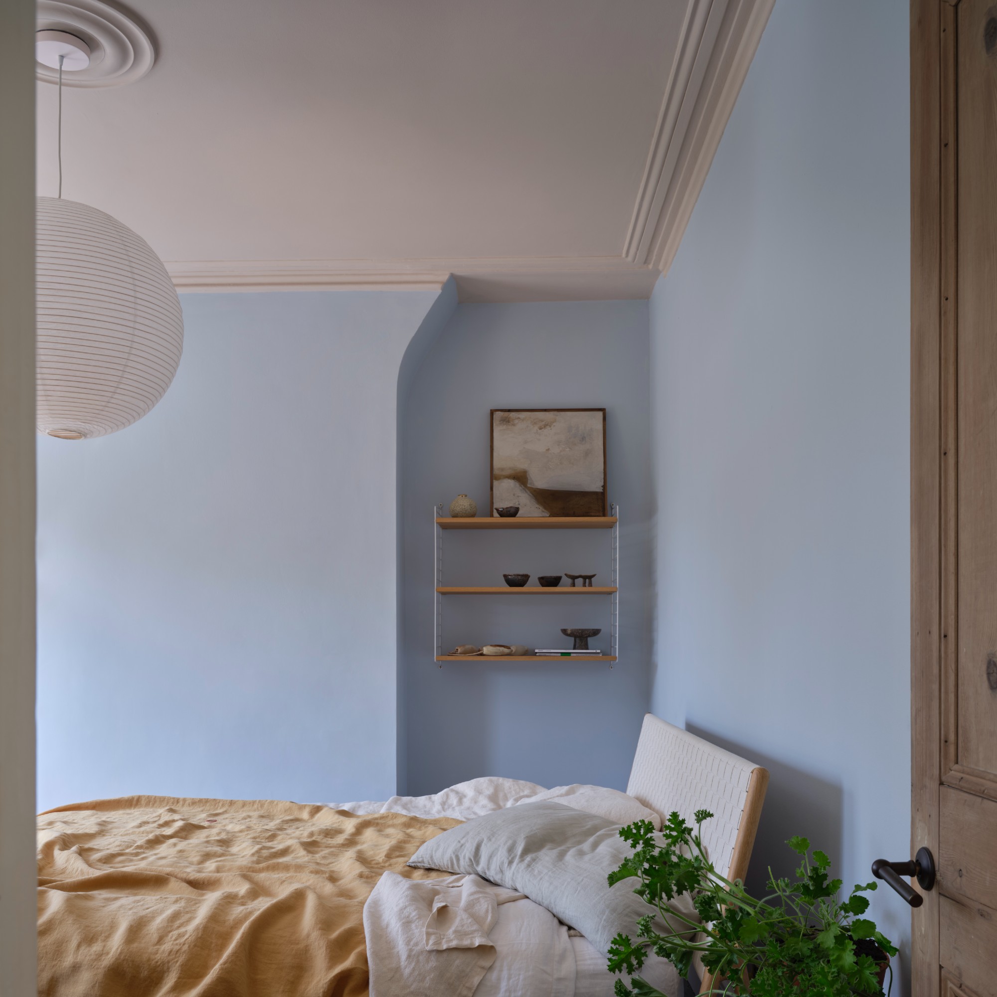 A soft blue painted bedroom with a blanket