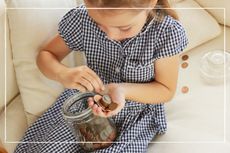 Child counting coins from a jar into her hand