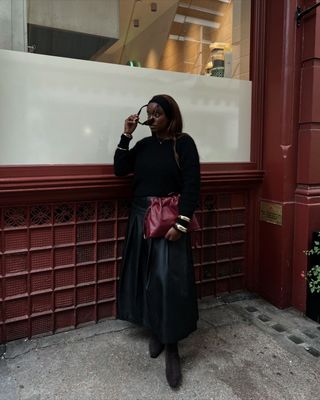 Rebekah in black leather skirt with red bag