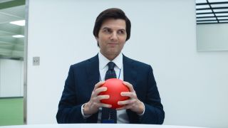 Adam Scott holding a red ball while sitting in an office in Severance.