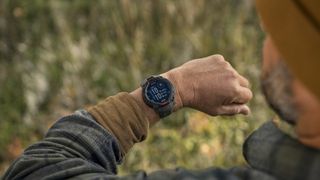 A photo of the Garmin Instinct 3 Solar on a man's wrist as he looks down at the main watch face