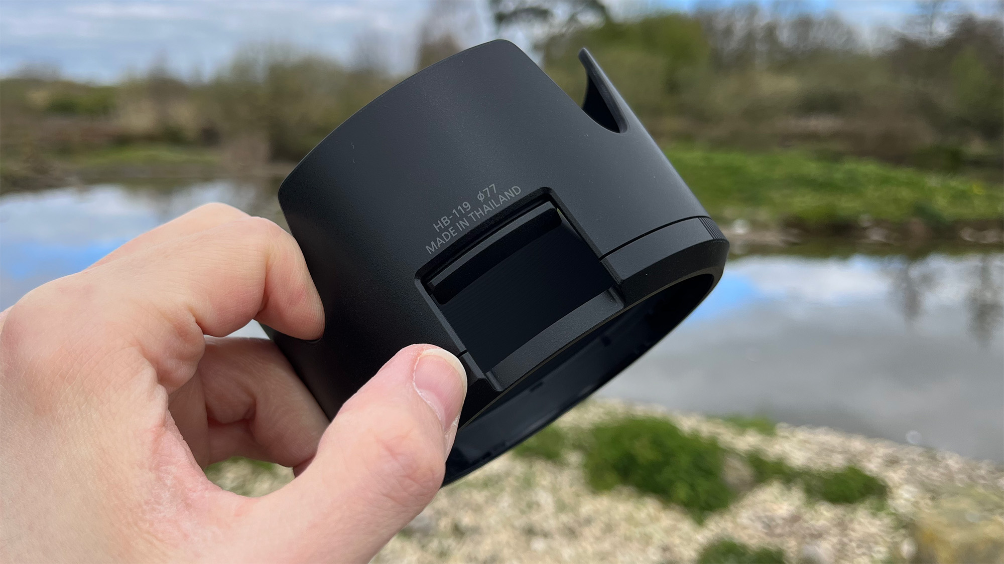 Mike Harris holding Nikon Z 70-200mm f/2.8 VR S II by a lake with vegetation and trees in the background