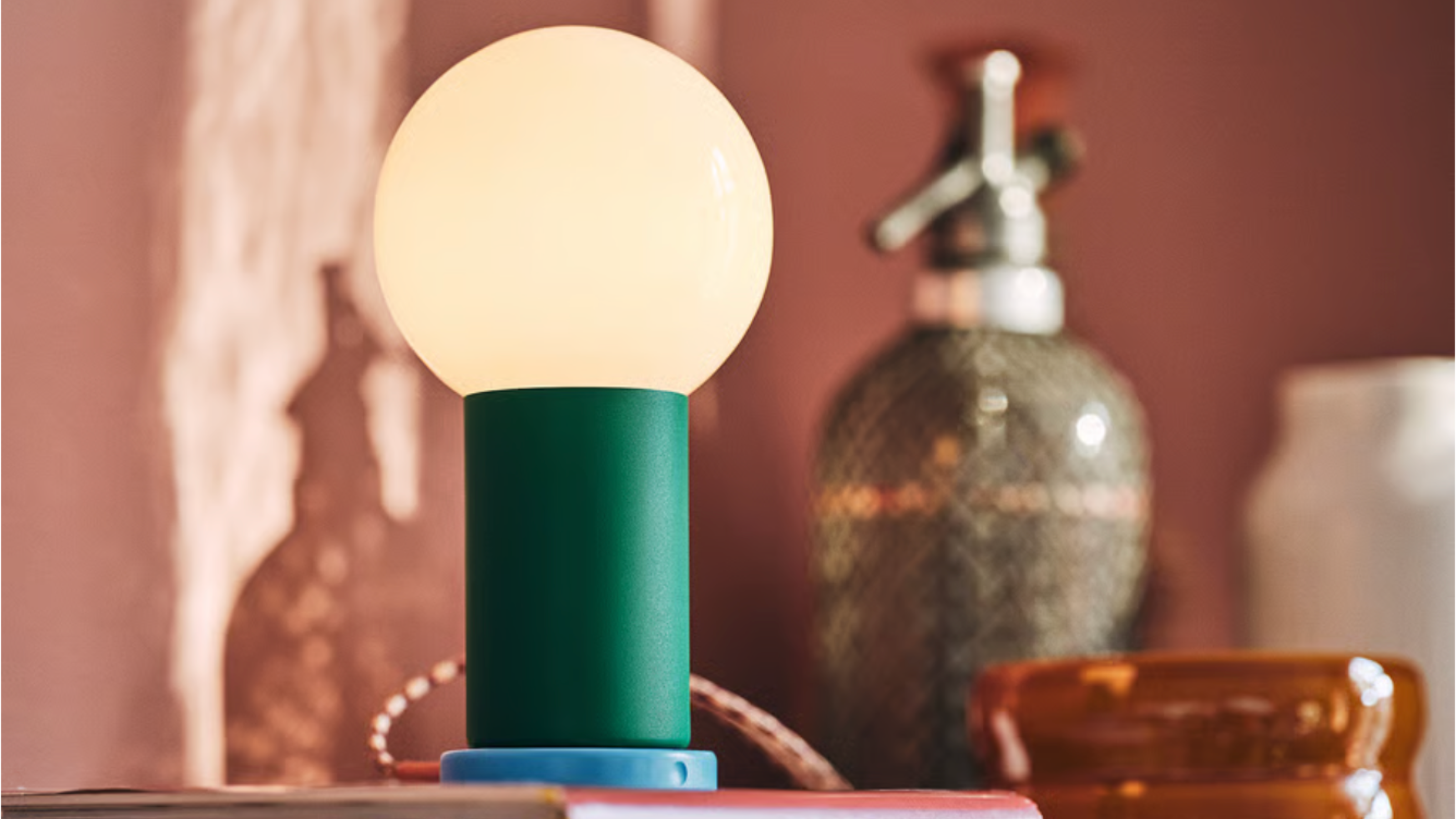 IKEA portable lamp with glowing bulb on green and blue stand