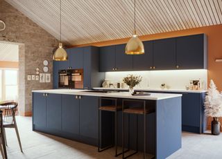 A dark blue kitchen with an island and brass accents