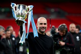 Pep Guardiola holds up the League Cup trophy after Manchester City's win over Aston Villa in the 2020 final at Wembley.