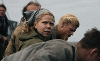 Alexandra Gjerpen as Hanna Wiig, looking over someone's shoulder aboard the boat
