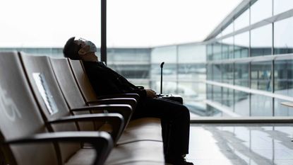 photo of man sitting slumped down among chairs in an airport