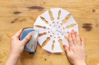 Make a hole in the top of the paper snowflakes