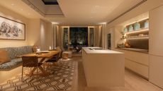 A kitchen with backlit shelves, spotlights, and a banquette dining area with wall lights