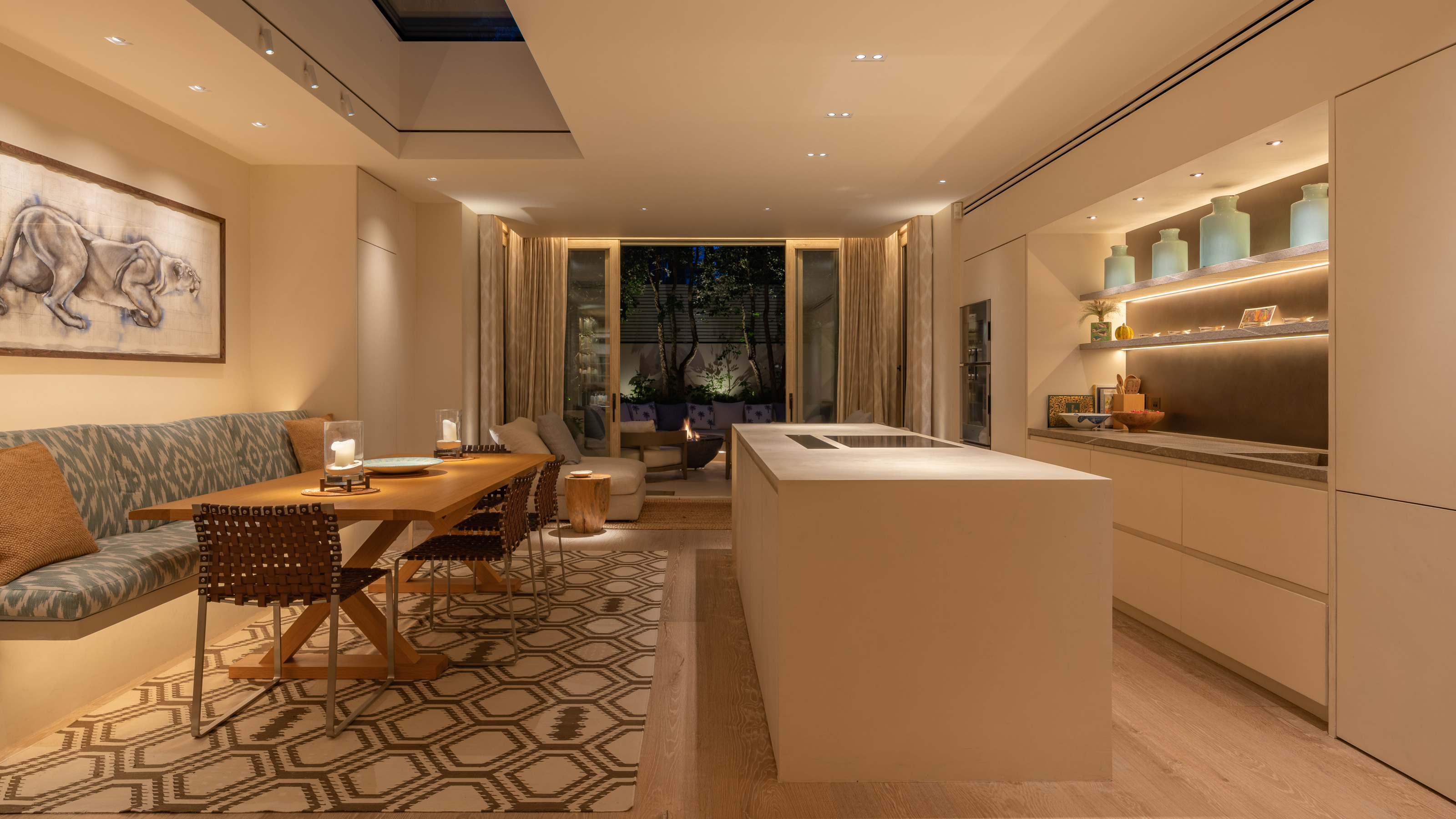 A kitchen with backlit shelves, spotlights, and a banquette dining area with wall lights