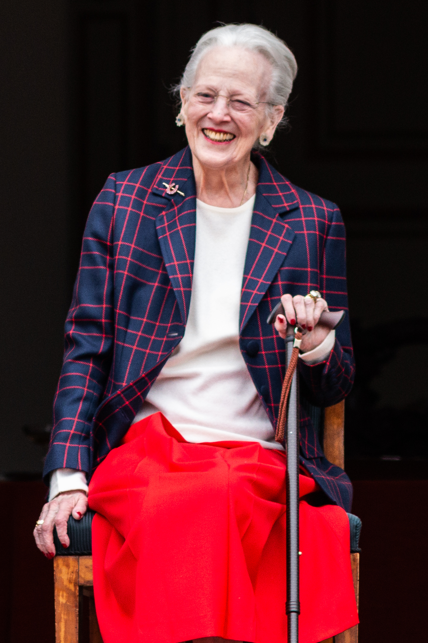 Queen Margrethe sitting in a chair holding a cane and smiling